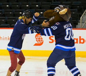 Mickey dances with Mick E Moose after beating Natalie Spooner and Meaghan Mikkelson at a hockey challenge on Amazing Race Canada 2 episode 6